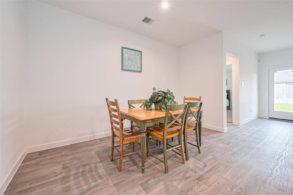 Recessed lighting casts a soft glow over the dining area, while the nearby glass-paneled door fills the space with daylight.