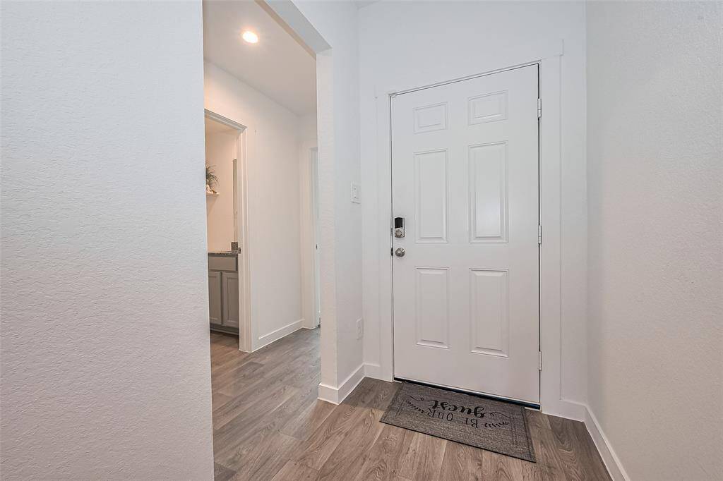 View of the front door from the inside reveals a thoughtful layout, with a blend of lighting and clean lines welcoming you in.