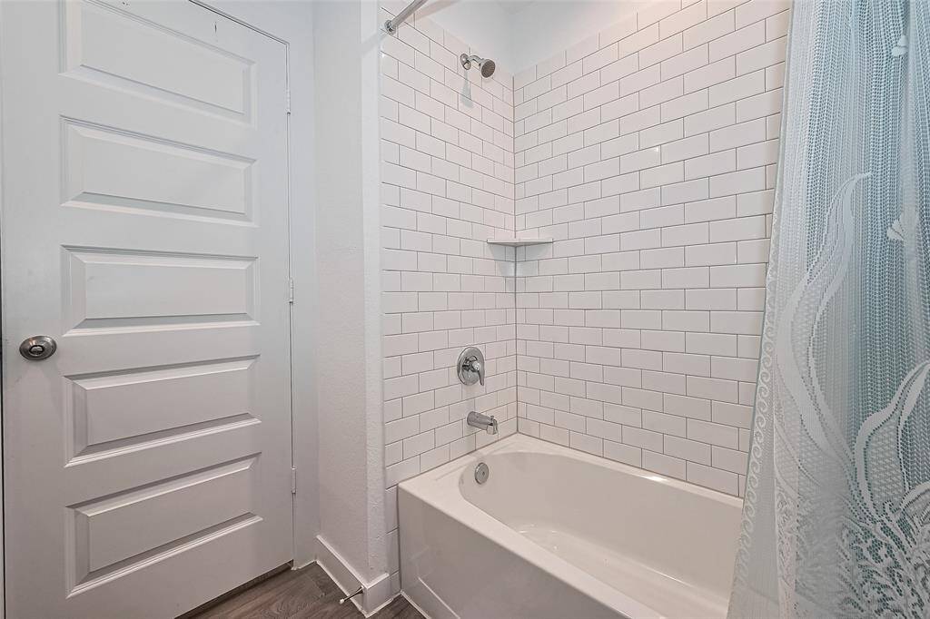 This full bathroom includes a classic shower-tub combo, neatly finished with timeless tilework.