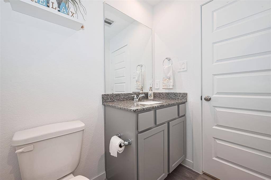 A scaled-down vanity with mirror and built-in storage echoes the elegance of the primary bathroom.