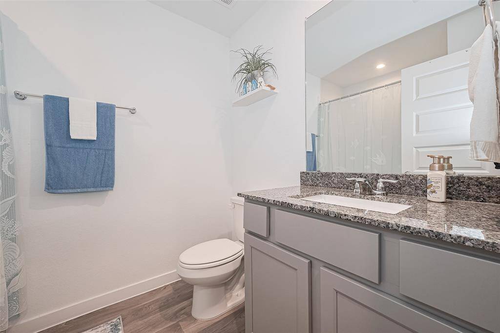Recessed lighting and wood-style laminate flooring give this bathroom a polished and contemporary feel.