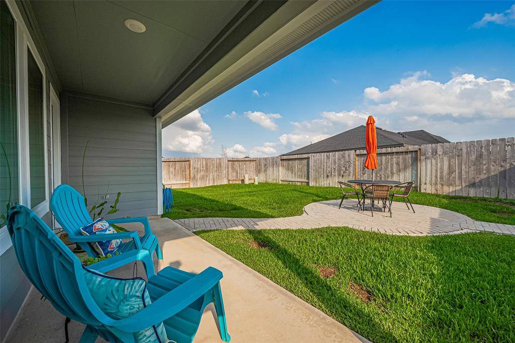 A covered back patio offers ample room for outdoor seating, overlooking a second uncovered patio that anchors the yard.