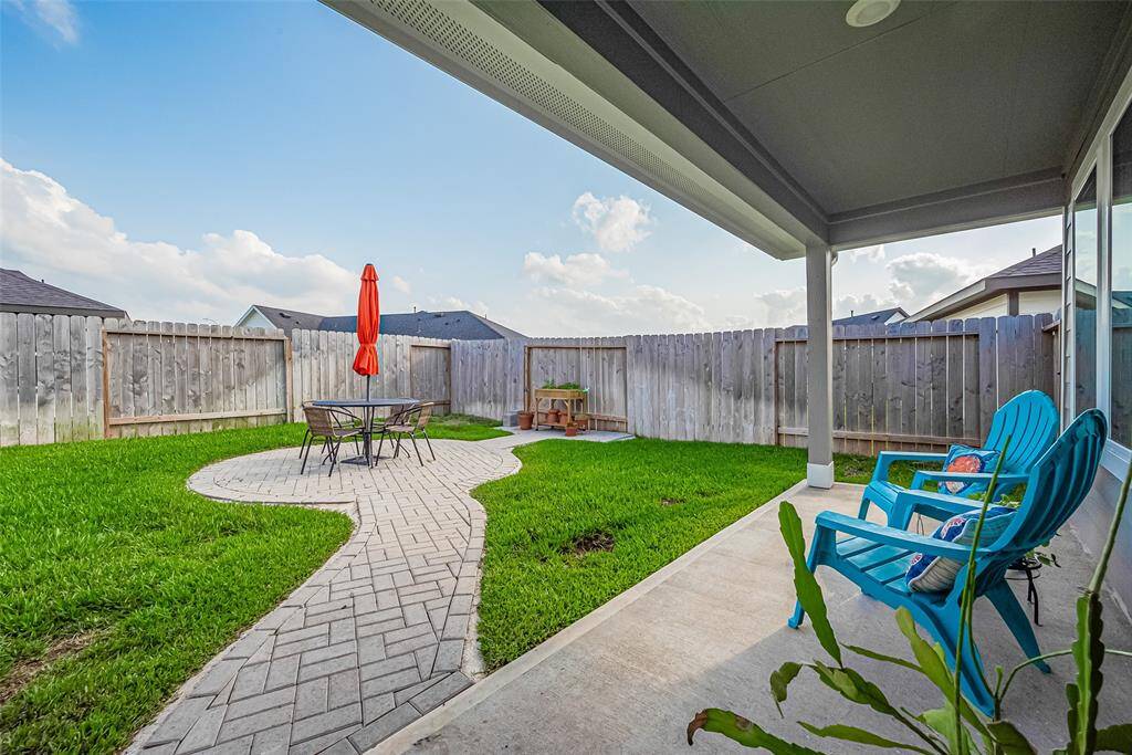 A stone walkway links the two patios, slicing through lush green grass to create a seamless outdoor experience.