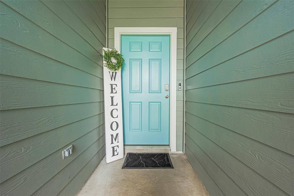 Front door painted in a welcoming hue adds charm and complements the home’s cool-toned siding.
