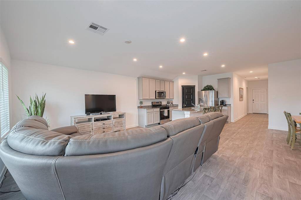 The living room flows seamlessly into the kitchen and dining areas, with a clear sightline extending back to the front door—perfect for entertaining.