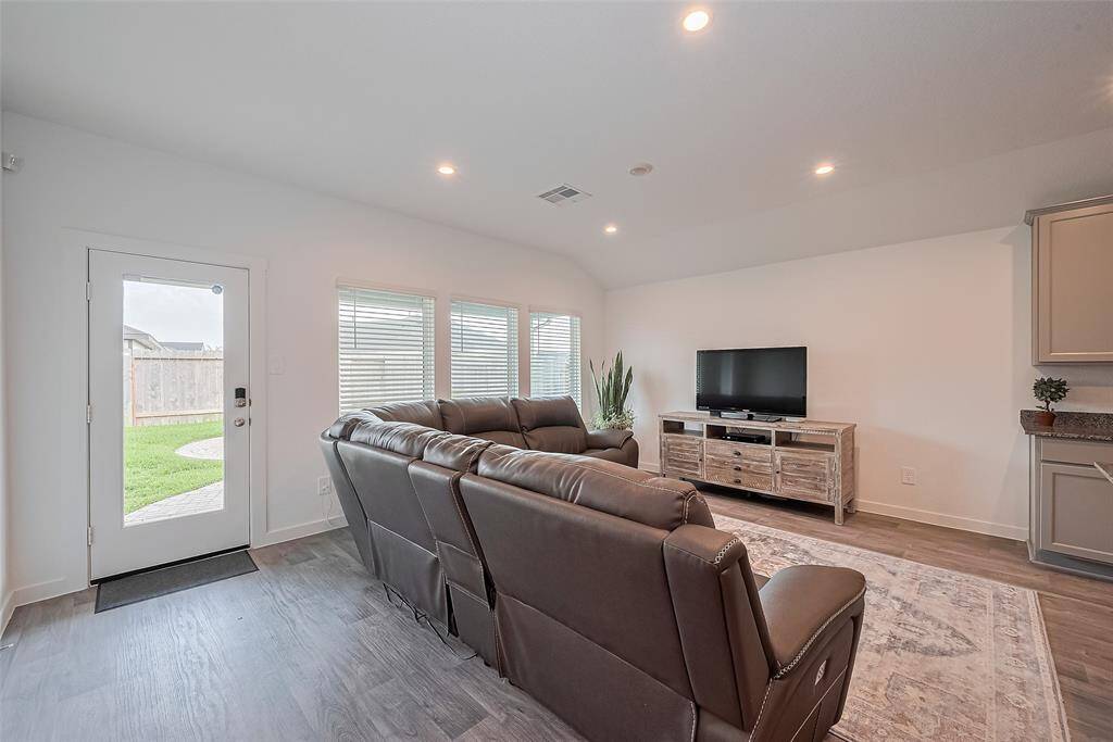 The large windows in the living room frame backyard views while a glass-paneled door provides effortless access to outdoor living.