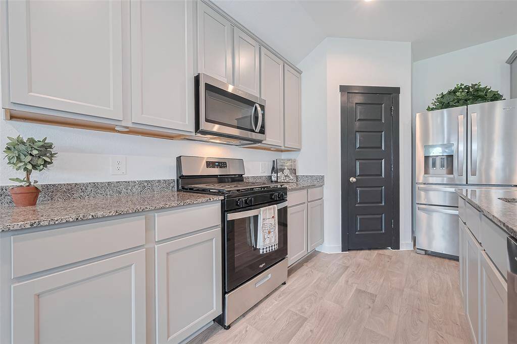 The kitchen features sleek, muted cabinetry above and below, lending a fresh and organized look to this stylish culinary space.