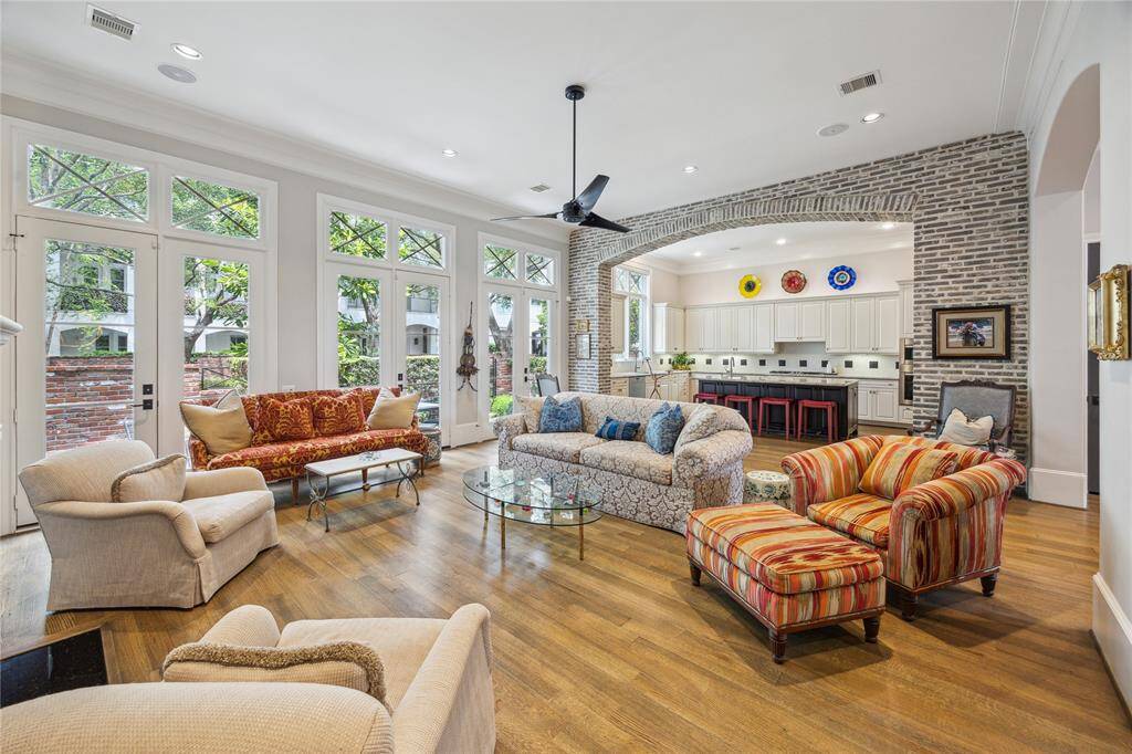The living room is filled with natural light, thanks to three sets of glass French doors and floor-to-ceiling windows that open out to the patio and courtyard, seamlessly blending indoor and outdoor living.