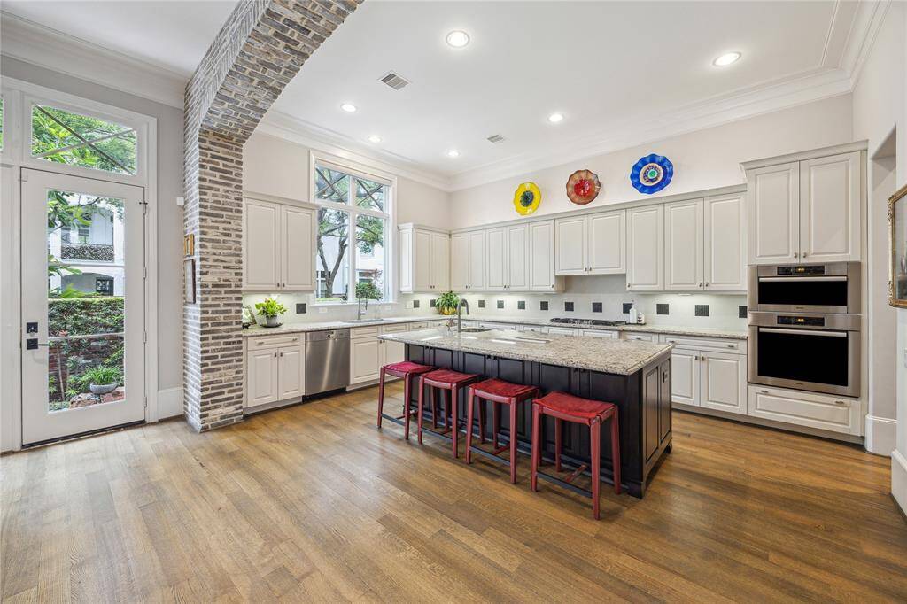 The fantastic, spacious kitchen boasts crisp white cabinetry, recessed lighting, large center island with a breakfast bar. double ovens, a steam oven, and a gas cooktop and offers easy access to the patio for effortless indoor-outdoor entertaining.