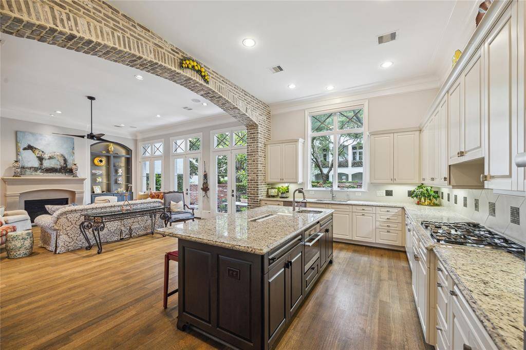 The gorgeous kitchen features granite countertops and a striking brick archway that opens into the living room, creating a sense of connection and character. The island also includes a built-in steam oven.