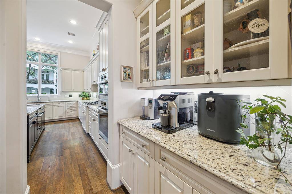 The convenient butler’s pantry features granite countertops, elegant glass-front cabinetry, and a spacious walk-in pantry.