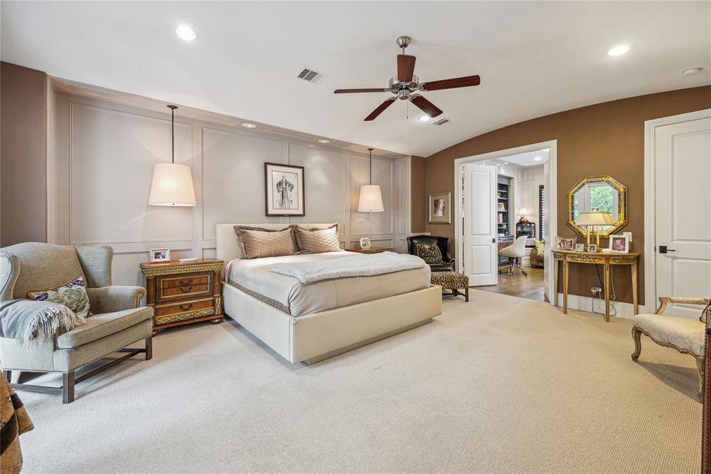 The primary suite is enhanced by a stylish wood accent wall, complemented by recessed and pendant lighting, and offers direct access to the home office.