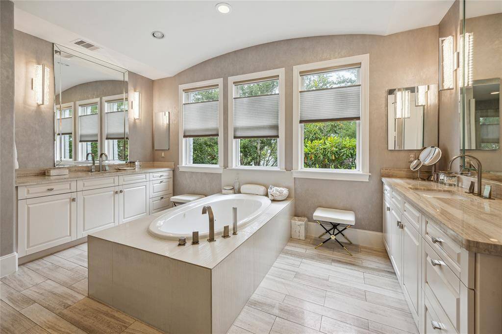 The gorgeous primary bath features dual sink vanities, three sunlit windows, a spacious jetted tub, and a walk-in shower—creating a spa-like atmosphere perfect for relaxation and daily comfort.