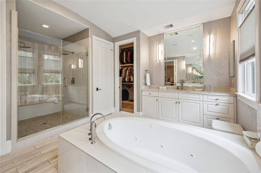 Across from the tub, a beautifully tiled walk-in shower features a sleek glass door, dual shower heads, and a built-in bench, offering both luxury and convenience for your daily routine.