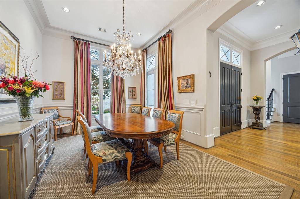 The spacious dining room showcases recessed lighting, elegant crown molding, and stylish chair rail accents, all complemented by expansive floor-to-ceiling windows that fill the space with natural light.