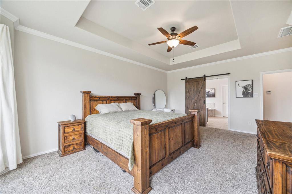 Look at that beautiful tray ceiling & custom built barn door leading into the primary bathroom!
