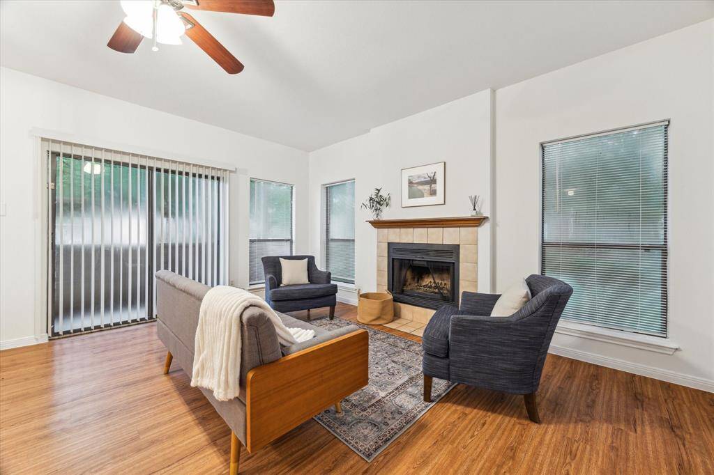 This cozy living room features warm floors, a central fireplace, and plenty of natural light from large windows.