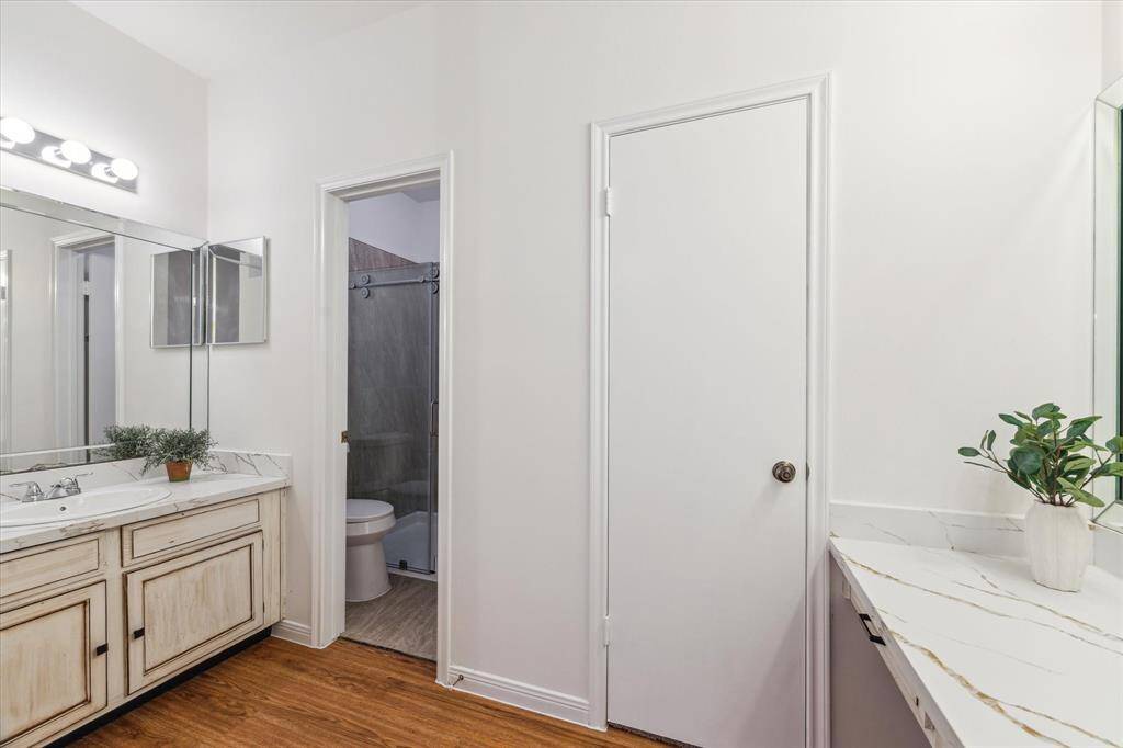 This bathroom features a double vanity with quartz countertops, large mirrors, and ample lighting.