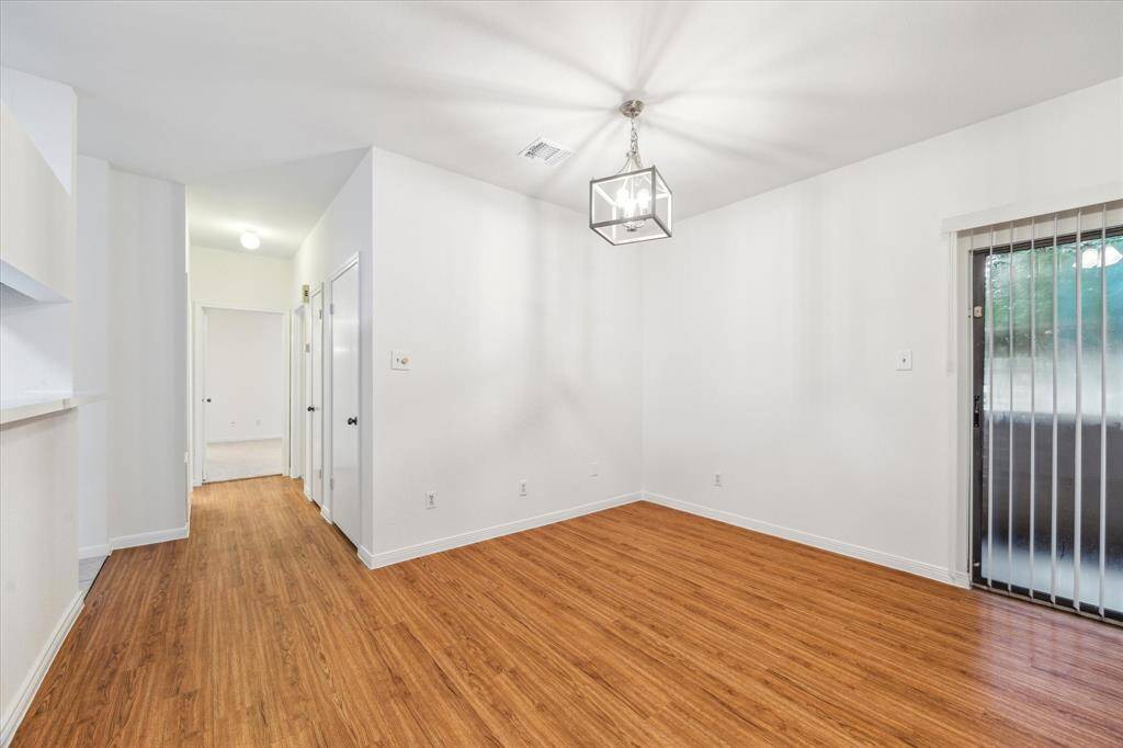 Bright, open dining room with warm flooring and modern lighting. Note the storage closets off of the hallway.