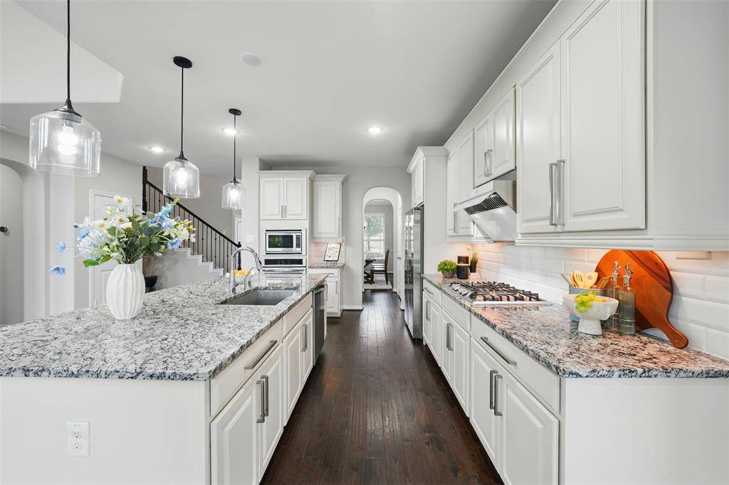 Sleek kitchen with granite counters, white cabinets, and stainless appliances.