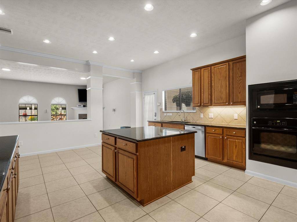 Kitchen with view of breakfast area, side door and kitchen window, built-in oven and microwave, center island and view of the living room and pool fountain through the windows.  So much to love in this room alone!