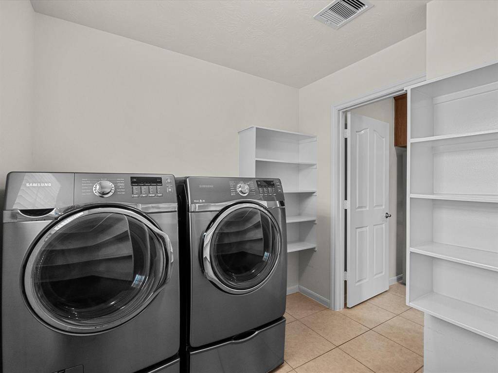 Utility or laundry room off of kitchen.  Featuring built-in shelves and plenty of space for essentials, laundry sorting and folding. This room also offers a window for natural light and serves as pantry storage, as well. Currently used for hanging clothes, there is space for a freezer or second refrigerator on the opposite wall