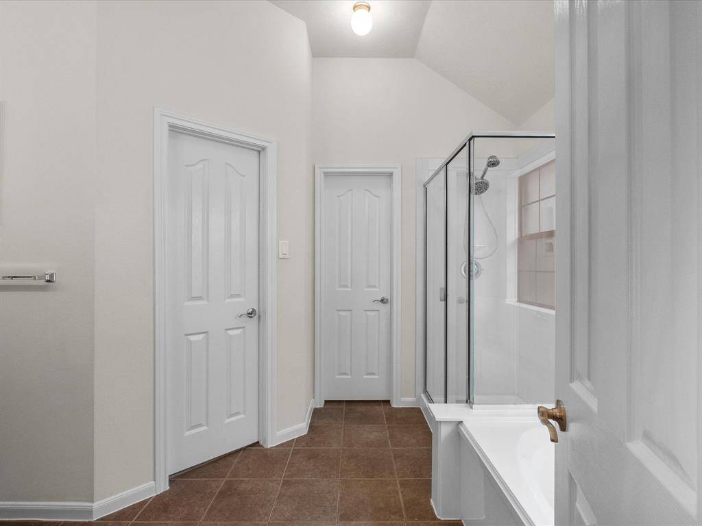 Primary bathroom is thoughtfully laid out with vanity and dressing mirror to the left, tub and separate shower to the right.  Straight ahead and to the left, primary closet door is closed and water closet with toilet immediately ahead.  Large window provides natural light to this space.
