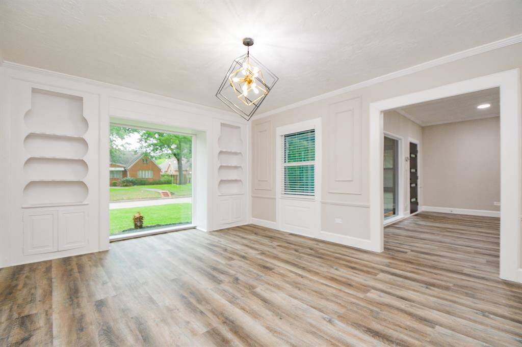 The open layout connects the adjacent Living room to this modern dining room. It features built-in shelving, and a large window with a view of the front yard.