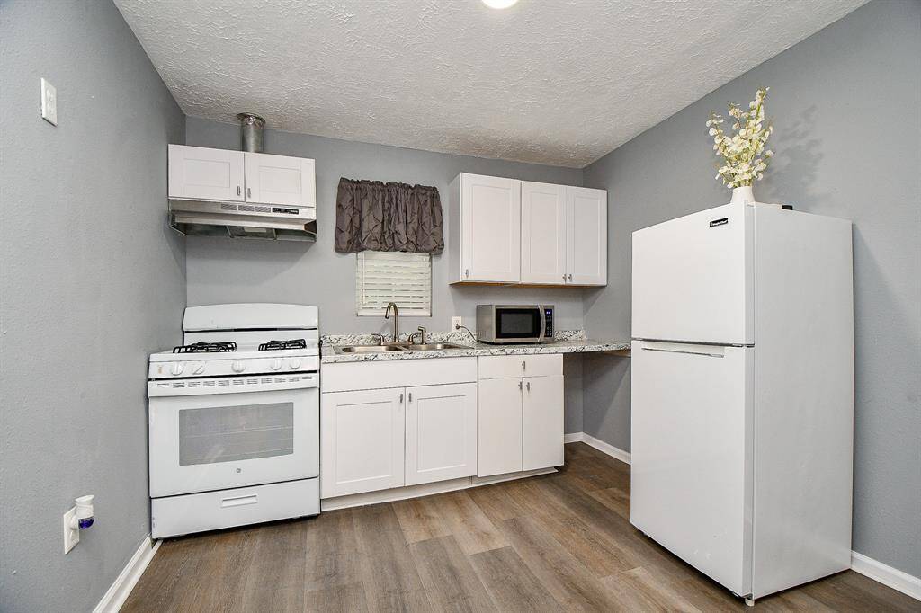 Welcome to the cottage that has a compact kitchen including a gas stove, microwave, and refrigerator.