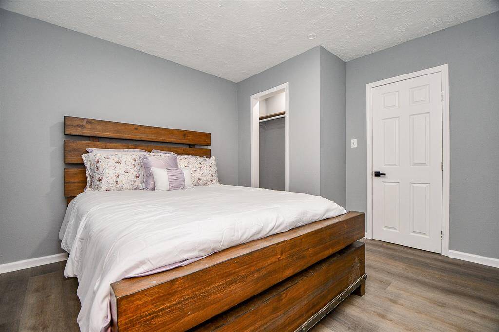 This cozy bedroom in the cottage features new grey laminate wood flooring. It includes an open closet space.