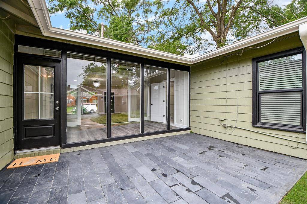 Modern patio with new slate tile flooring and large glass windows leading into the house. Offering an inviting outdoor space.