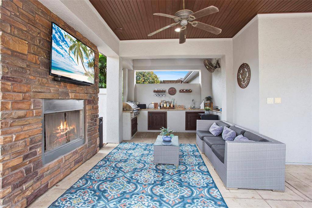Resort style covered patio with outdoor fireplace and outdoor kitchen.
