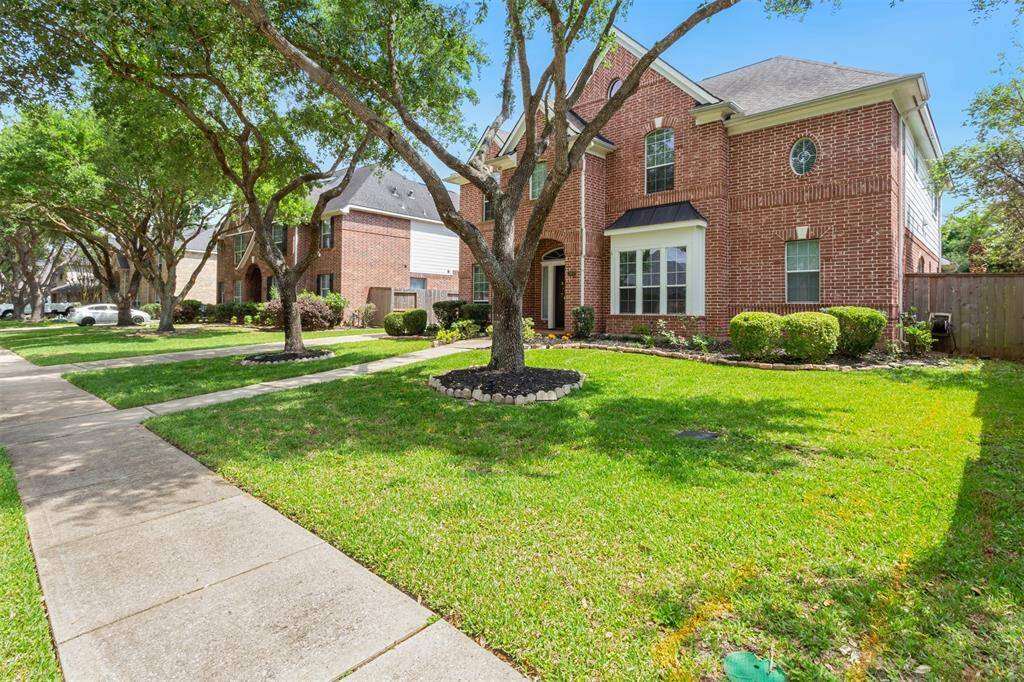 Lush front yard with two majestic oak trees and stunning landscaping.
