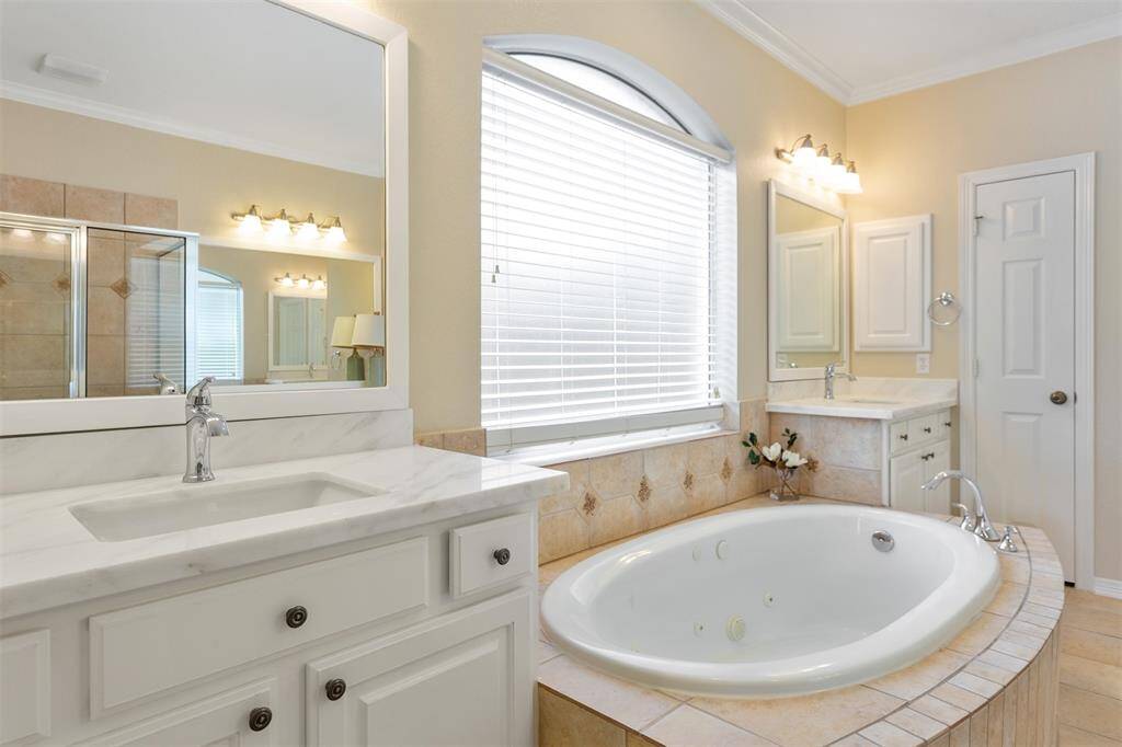 Elegant primary bathroom featuring new quartz sinks and a luxurious soaking tub.