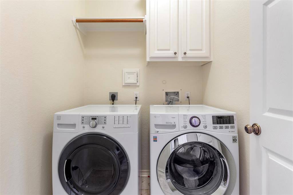 Efficient laundry space with modern washer and dryer, ample storage, and shelving for convenience.