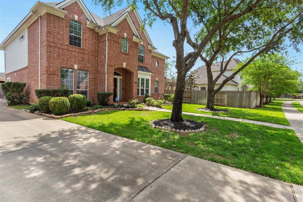 Charming front yard with lush greenery and mature trees, offering a welcoming curb appeal.