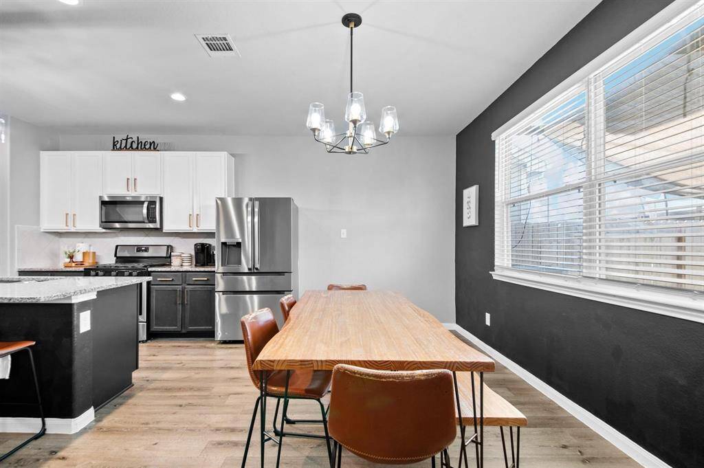 The dining area, adjacent to the kitchen, features a large window that fills the space with natural light. A stylish chandelier adds a touch of elegance, creating a warm and inviting setting for meals and gatherings.
