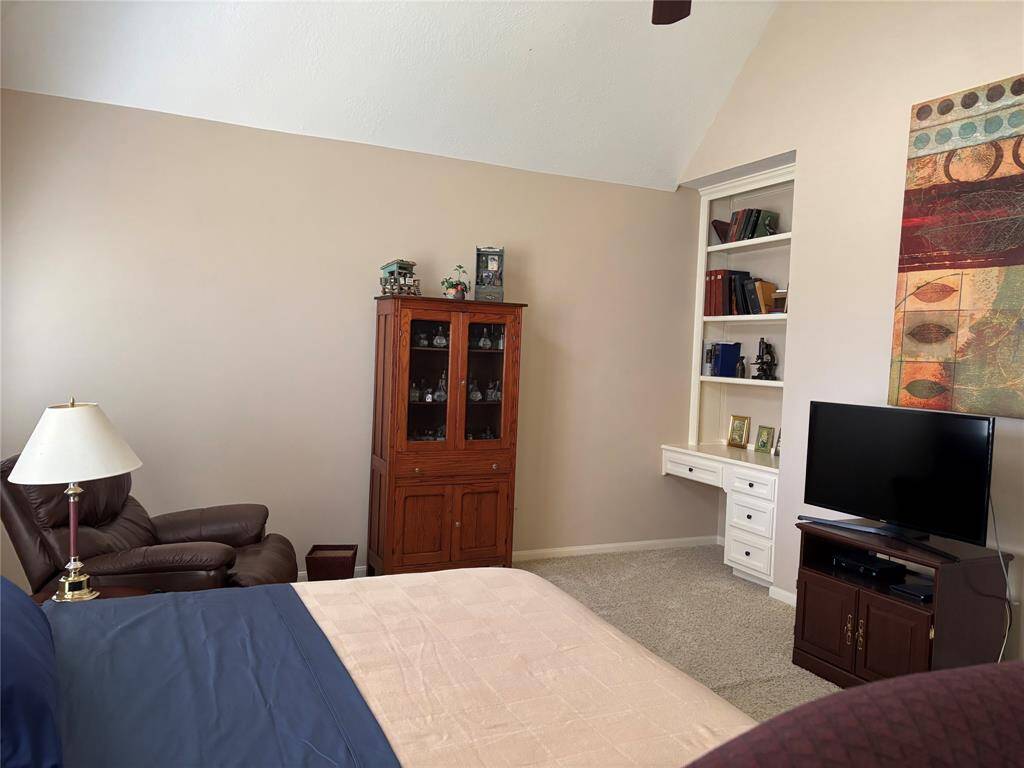 Large primary bedroom featuring a convenient built-in desk and bookshelves.