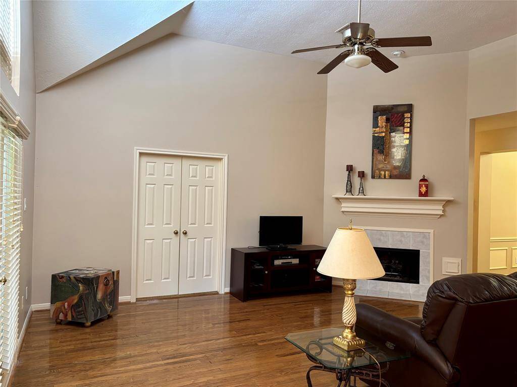 A spacious family room with vaulted ceilings, a cozy fireplace, and hardwood flooring.