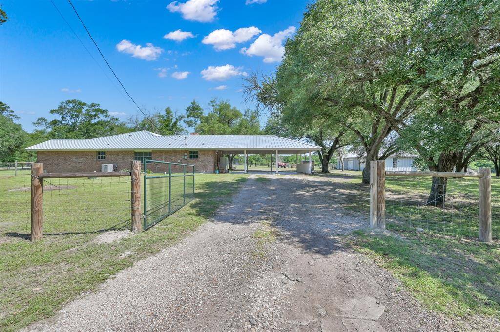A gated entrance leads to a covered carport, providing ample outdoor space and a rural feel, perfect for those seeking tranquility and privacy.
