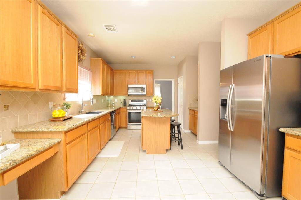 The kitchen is designed with both functionality and style in mind, featuring sleek countertops, and an island that provides additional workspace and seating