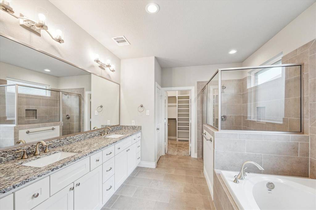 Luxurious primary bathroom featuring a separate tub and glass-enclosed shower.