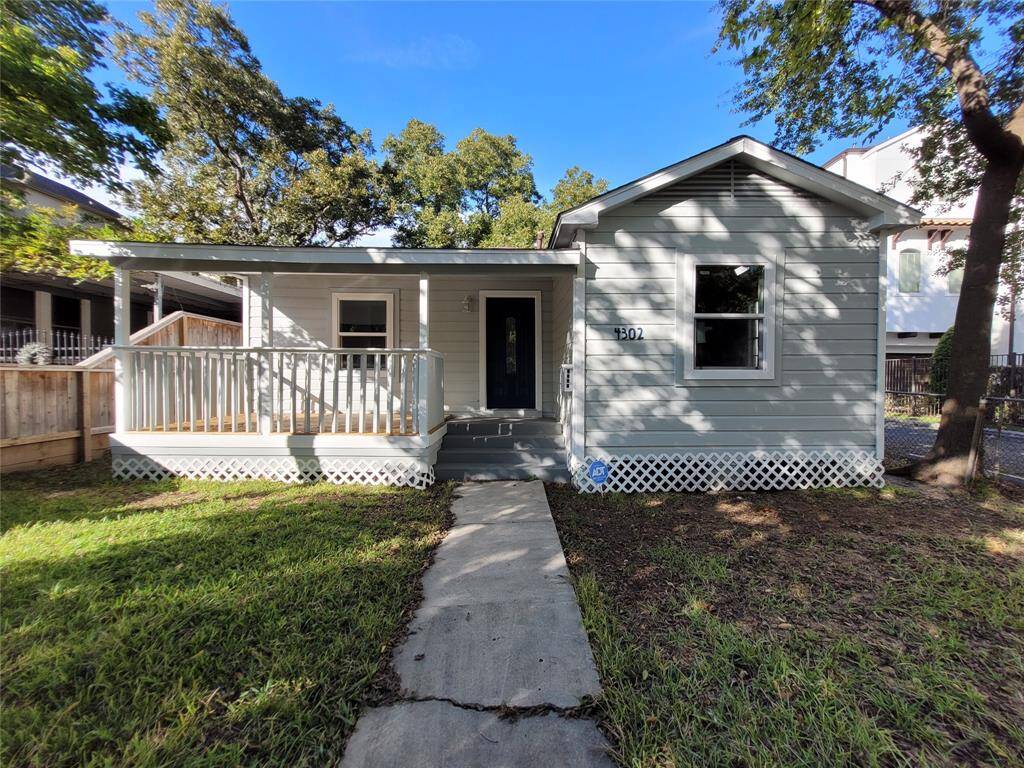 Charming single-story home with a welcoming front porch, nestled in a lush green yard. The exterior features light gray siding and white trim, offering a fresh and inviting appearance. A pathway leads to the entrance, surrounded by mature trees providing shade and privacy.