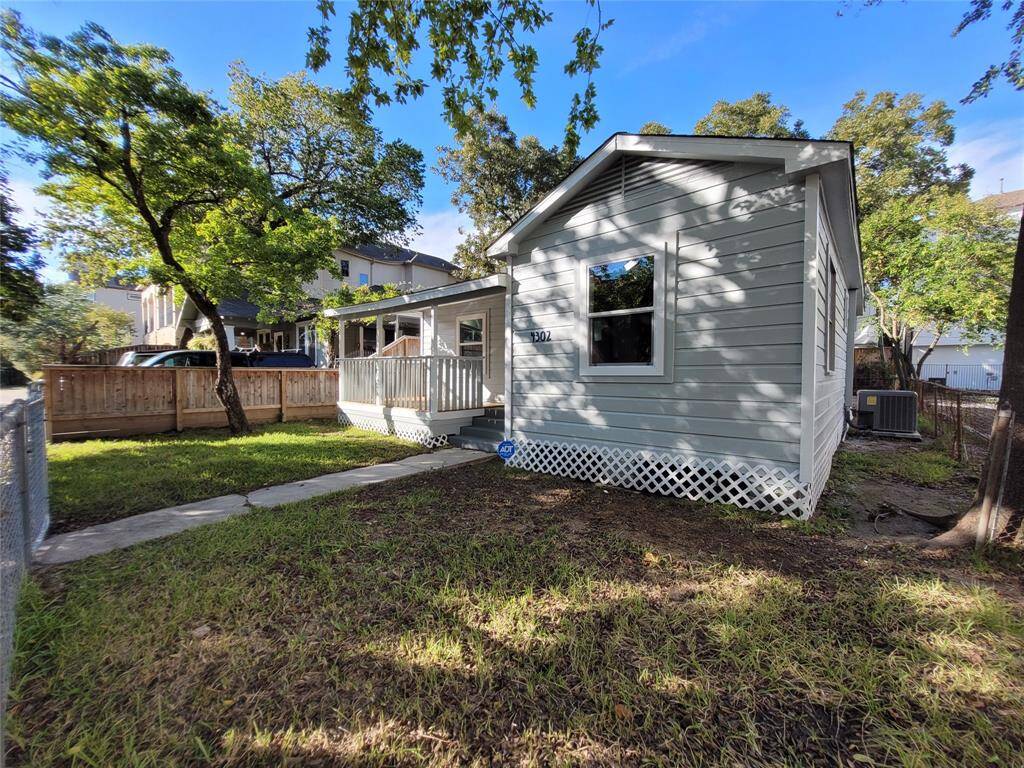 It features a cozy front porch, a fenced yard, and mature trees providing shade. Ideal for a peaceful residential setting.