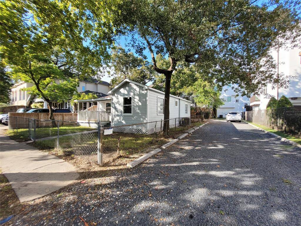 Charming single-story home with a light exterior, nestled in a tree-lined neighborhood. Features a fenced yard and gravel driveway, offering privacy and ample parking. Ideal for those seeking a cozy and accessible living space.