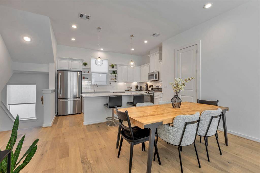 The light brown wood floors throughout the kitchen, dining, and living areas beautifully complement the crisp white walls, creating a warm and inviting atmosphere.