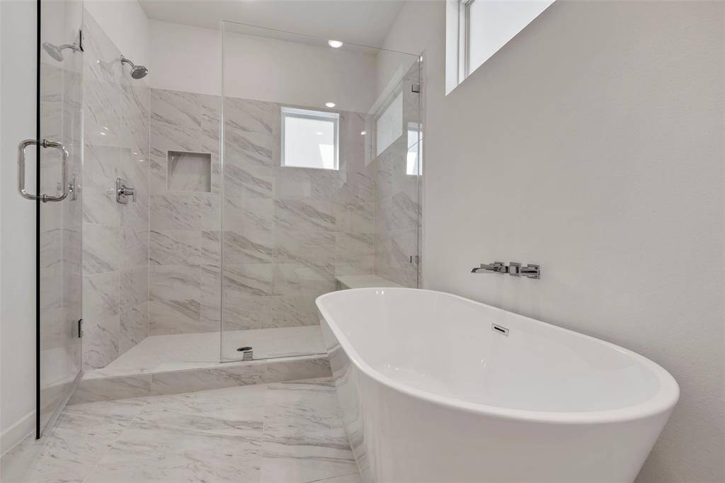 Another view of the main bathroom, showcasing the tub and the sleek glass-enclosed shower area.