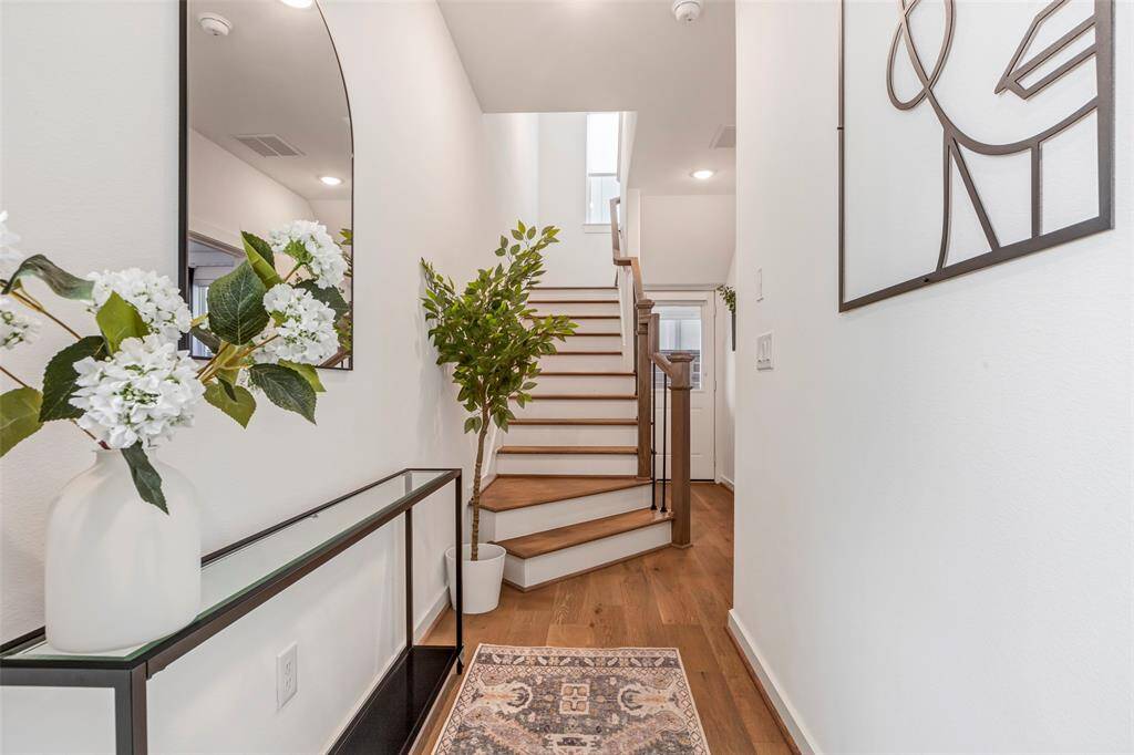 From the foyer, a graceful staircase leads to the second floor, while a hallway to the right offers access to a main-level bedroom and a peek at the back door—blending style with smart layout.