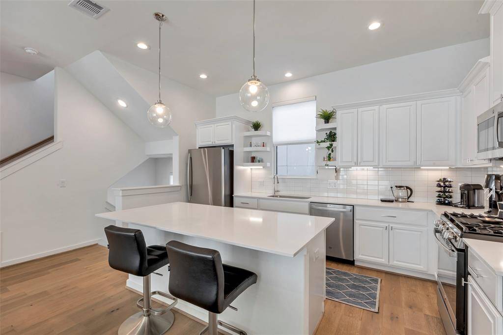 This view of the kitchen highlights its thoughtful layout, with a glimpse of the staircase leading to both the first and third floors, adding a sense of openness and flow to the home.