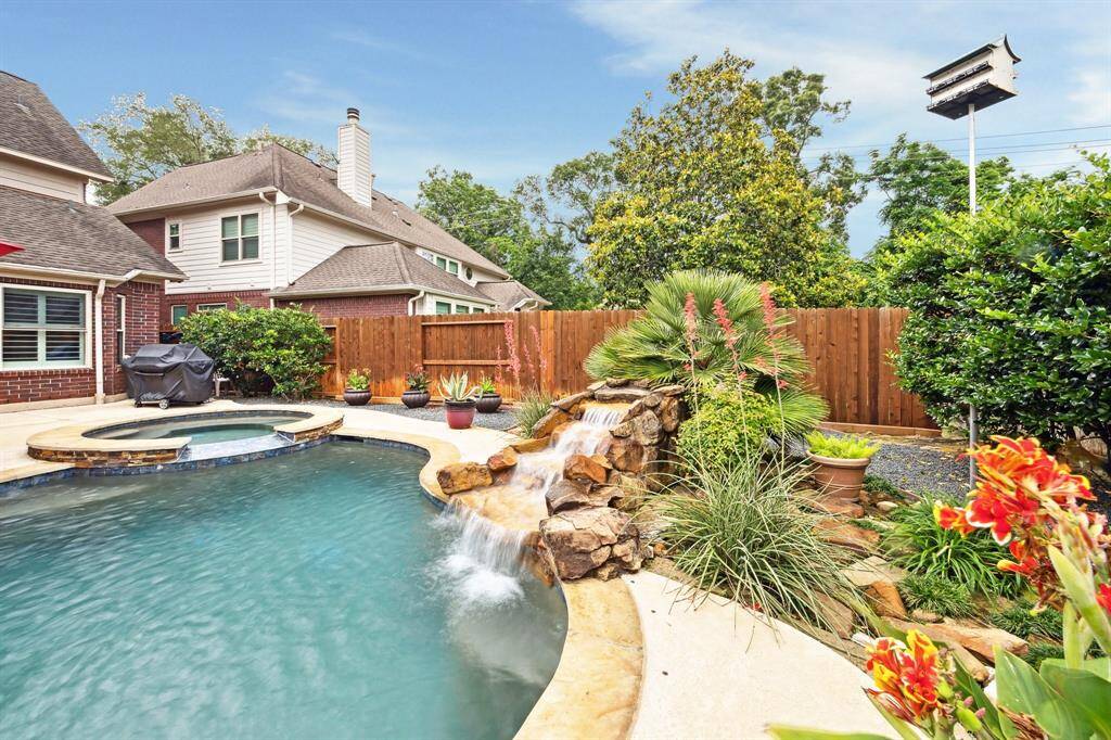 BACKYARD OASIS FEATURES A REFRESHING WATER FALL, AND LUSH LANDSCAPING